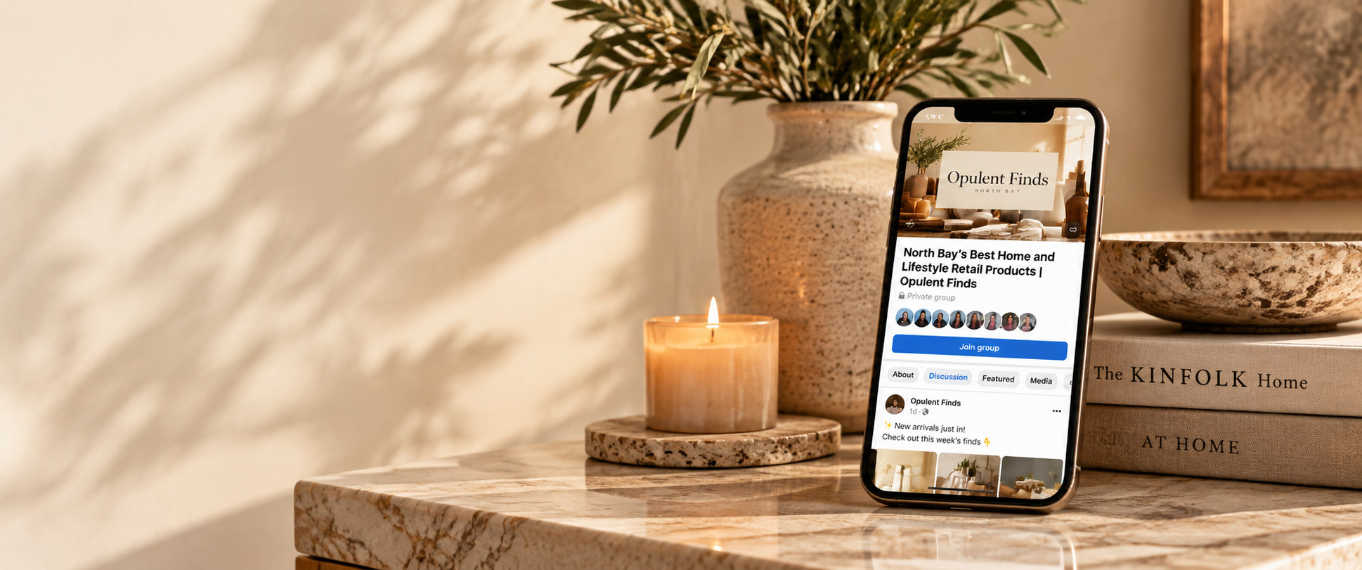 Opulent Finds Facebook group shown on a phone beside a candle and ceramic vase